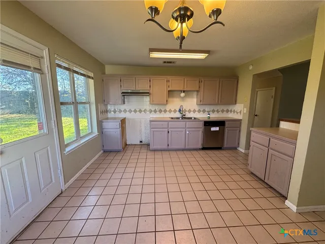 a large kitchen with a stove a refrigerator a sink dishwasher and wooden cabinets