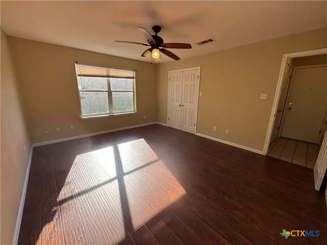 a view of empty room with wooden floor and fan