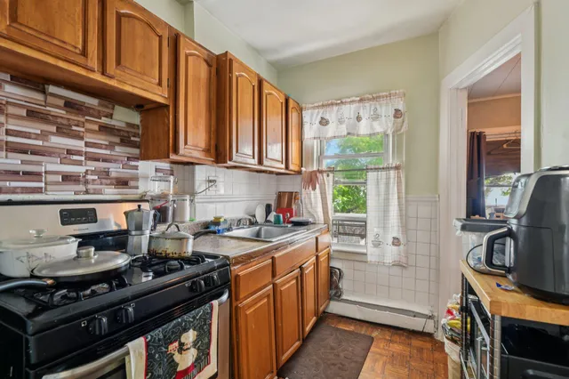 a kitchen with a stove a sink and wooden floor