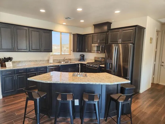 a kitchen with stainless steel appliances granite countertop a sink refrigerator and cabinets