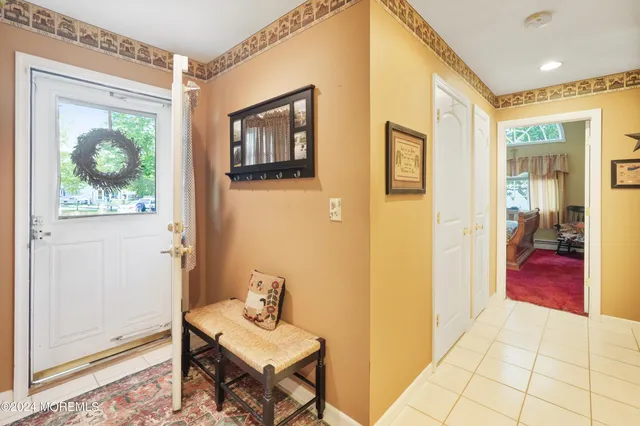 a view of a hallway that has a couch and a dining table next to a window