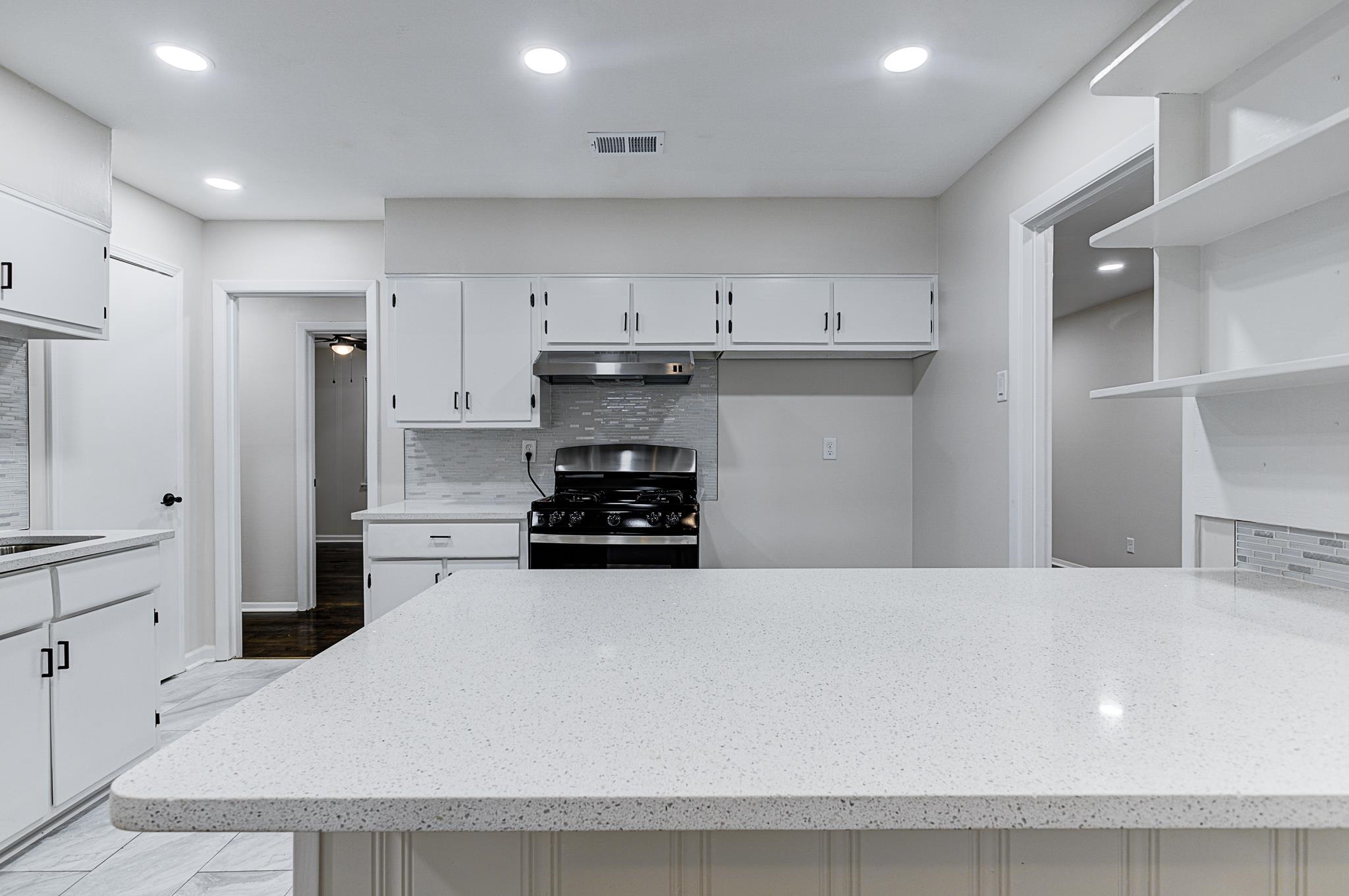 5094 Lochinvar Road Memphis, TN 38116 - Photo 6 of 23 Kitchen with white cabinetry, Quartz countertops, gas range, and decorative backsplash