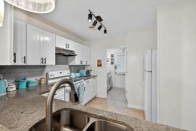 a kitchen with stainless steel appliances granite countertop a sink refrigerator and cabinets