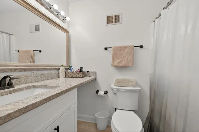 a bathroom with a granite countertop toilet sink and mirror