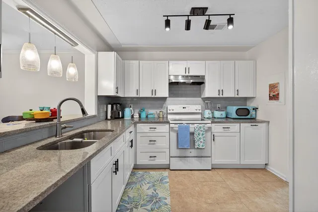 a kitchen with white cabinets a sink and appliances