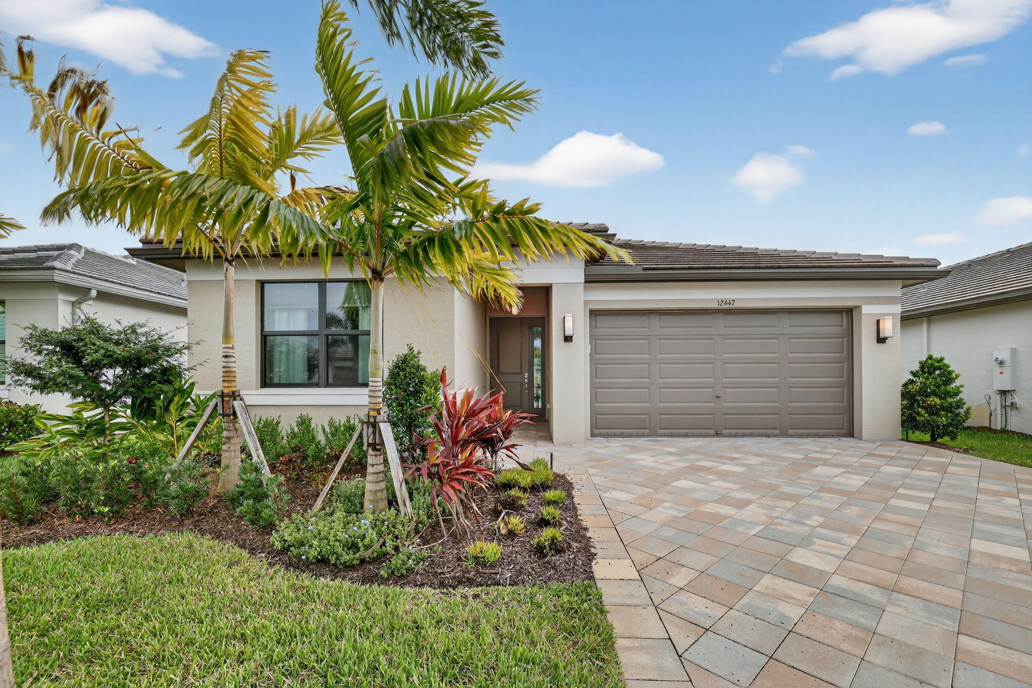 12447 Southwest Blue Mangrove Parkway Port St. Lucie, FL 34987 - Photo 1 of 80 a front view of yellow house with a yard and potted plants