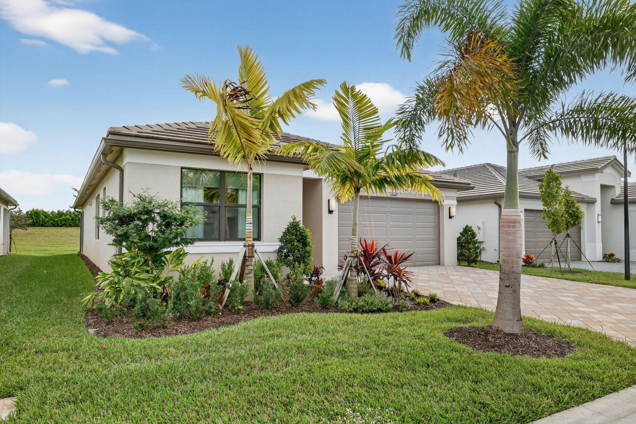 12447 Southwest Blue Mangrove Parkway Port St. Lucie, FL 34987 - Photo 3 of 80 a view of a white house with a small yard and palm trees