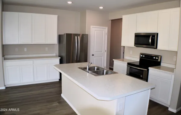 a kitchen with a sink a microwave a refrigerator and cabinets