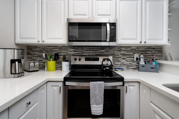 a kitchen with stainless steel appliances granite countertop white cabinets and a stove a oven with white countertops