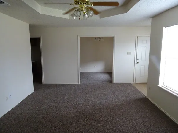 an empty room with a chandelier fan and windows
