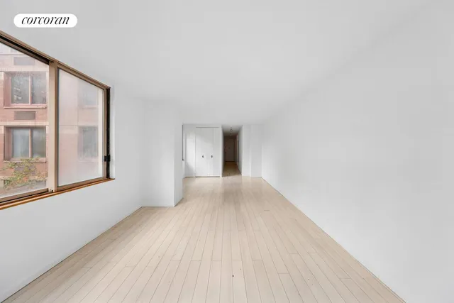 a view of an empty room with a window and wooden floor