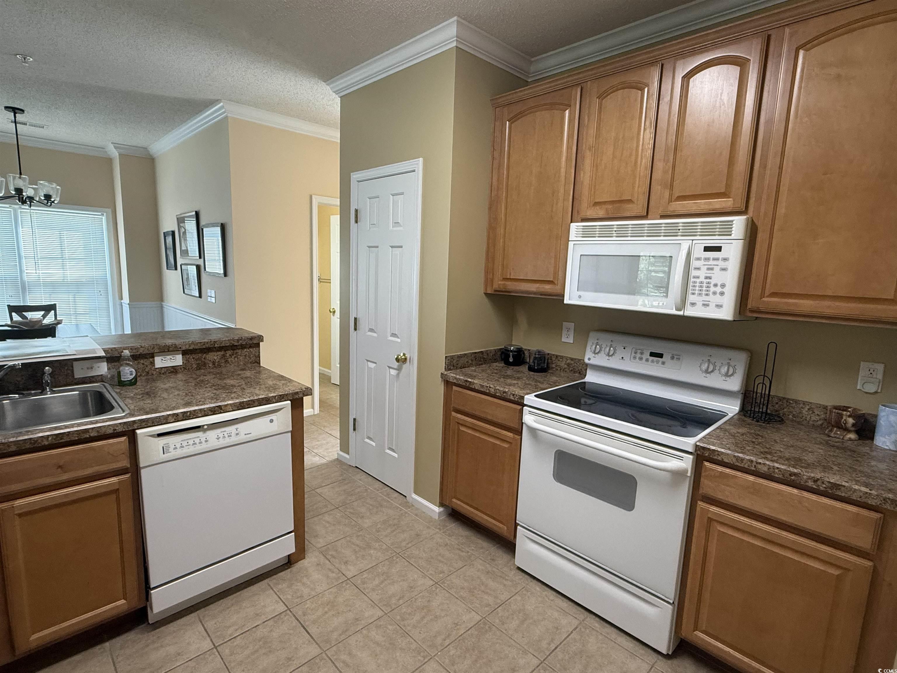 5858 Longwood Drive, Unit #204 Murrells Inlet, SC 29576 - Photo 5 of 13 Kitchen featuring white appliances, dark countertops, a textured ceiling, crown molding, and decorative light fixtures