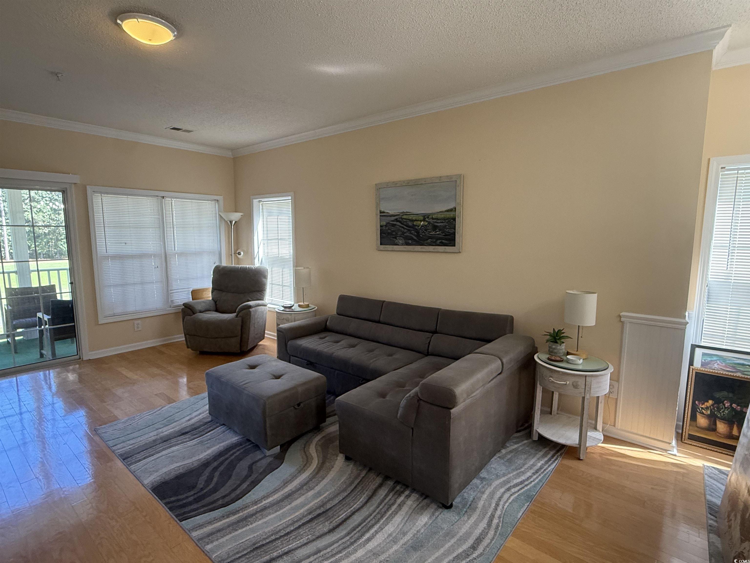 5858 Longwood Drive, Unit #204 Murrells Inlet, SC 29576 - Photo 7 of 13 Living room with crown molding, plenty of natural light, a textured ceiling, and wood finished floors
