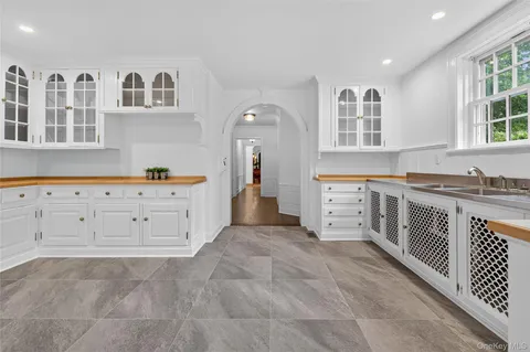 a large white kitchen with granite countertop a lot of cabinets and wooden floor