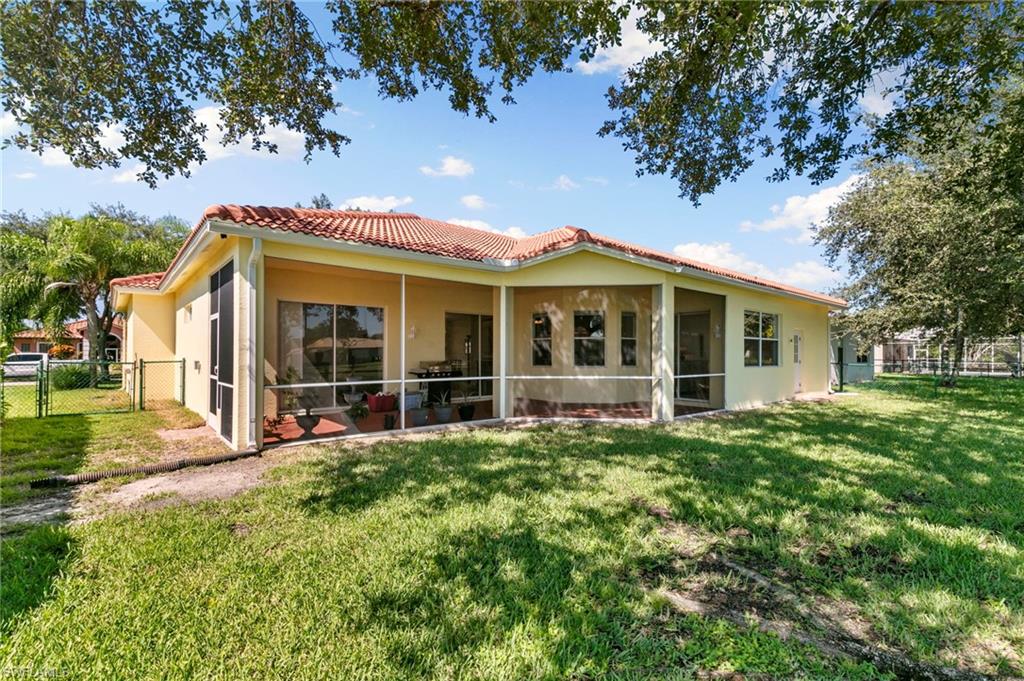860 Grand Rapids Boulevard Naples, FL 34120 - Photo 35 of 44 a view of a house with a large tree and a yard with lawn chairs