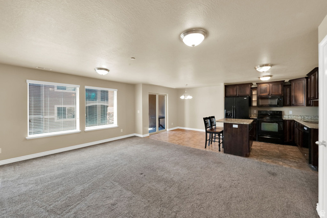 909 South Main Street, Unit G Layton, UT 84041 - Photo 8 of 25 Open-concept living area featuring a kitchen with dark wood-finish cabinetry, black appliances, and stone countertops