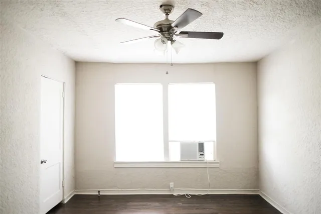 an empty room with a window and a ceiling fan