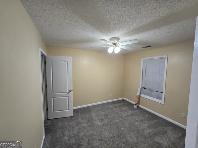 an empty room with windows and fan