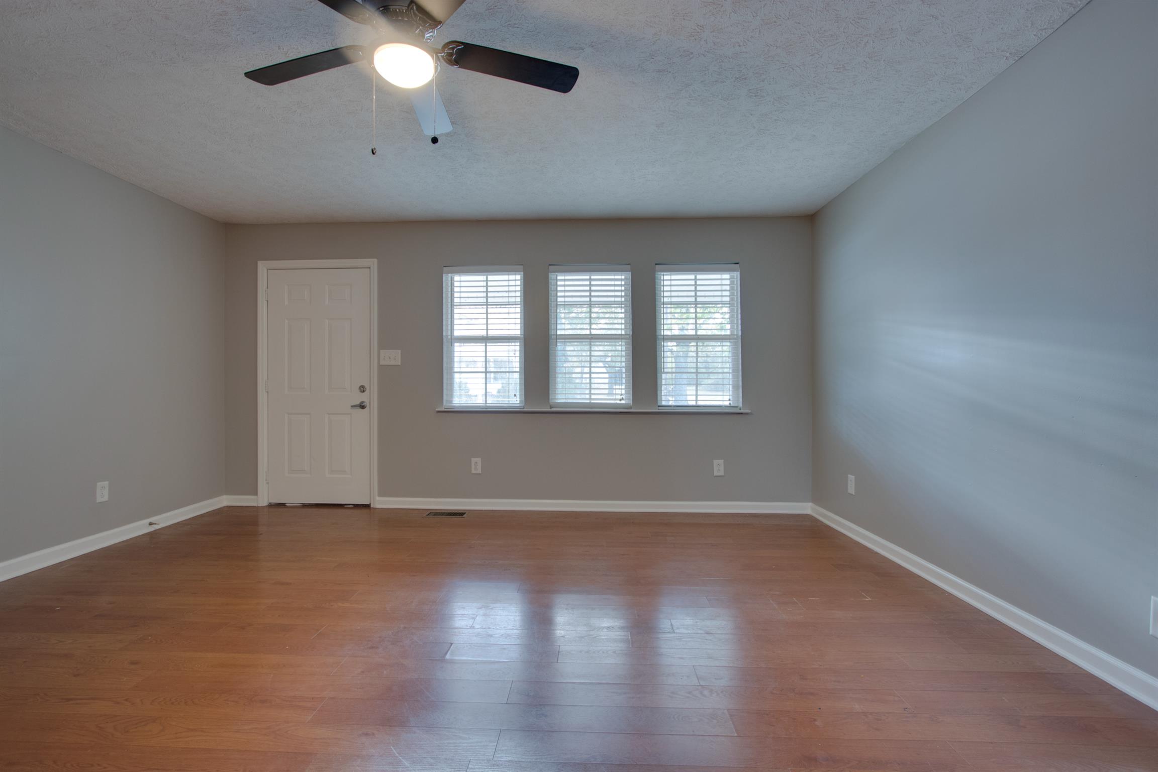 201 High Street Alexandria, TN 37012 - Photo 5 of 23 an empty room with wooden floor chandelier fan and windows