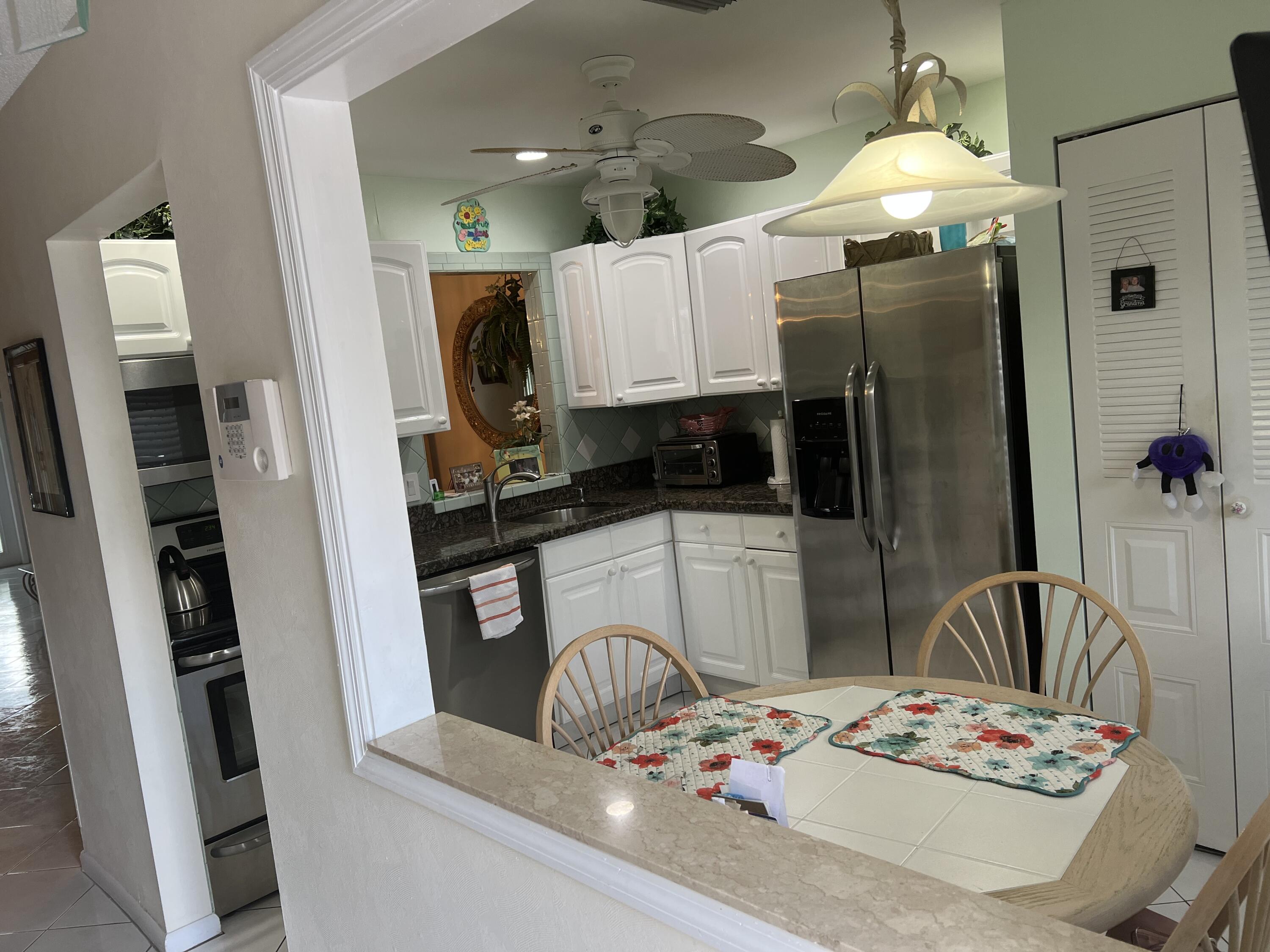 6877 Moonlit Drive Delray Beach, FL 33446 - Photo 3 of 45 a kitchen with stainless steel appliances kitchen island granite countertop a refrigerator a stove a microwave oven with white cabinets and wooden floor
