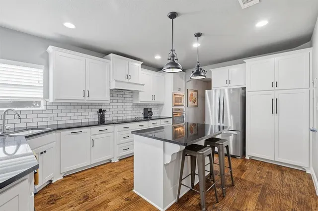 a kitchen with stainless steel appliances granite countertop a sink a refrigerator and a stove