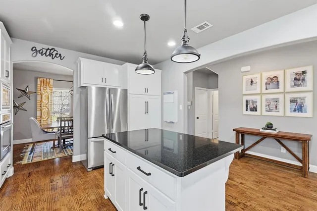 a kitchen with granite countertop a sink a center island a counter space and cabinets