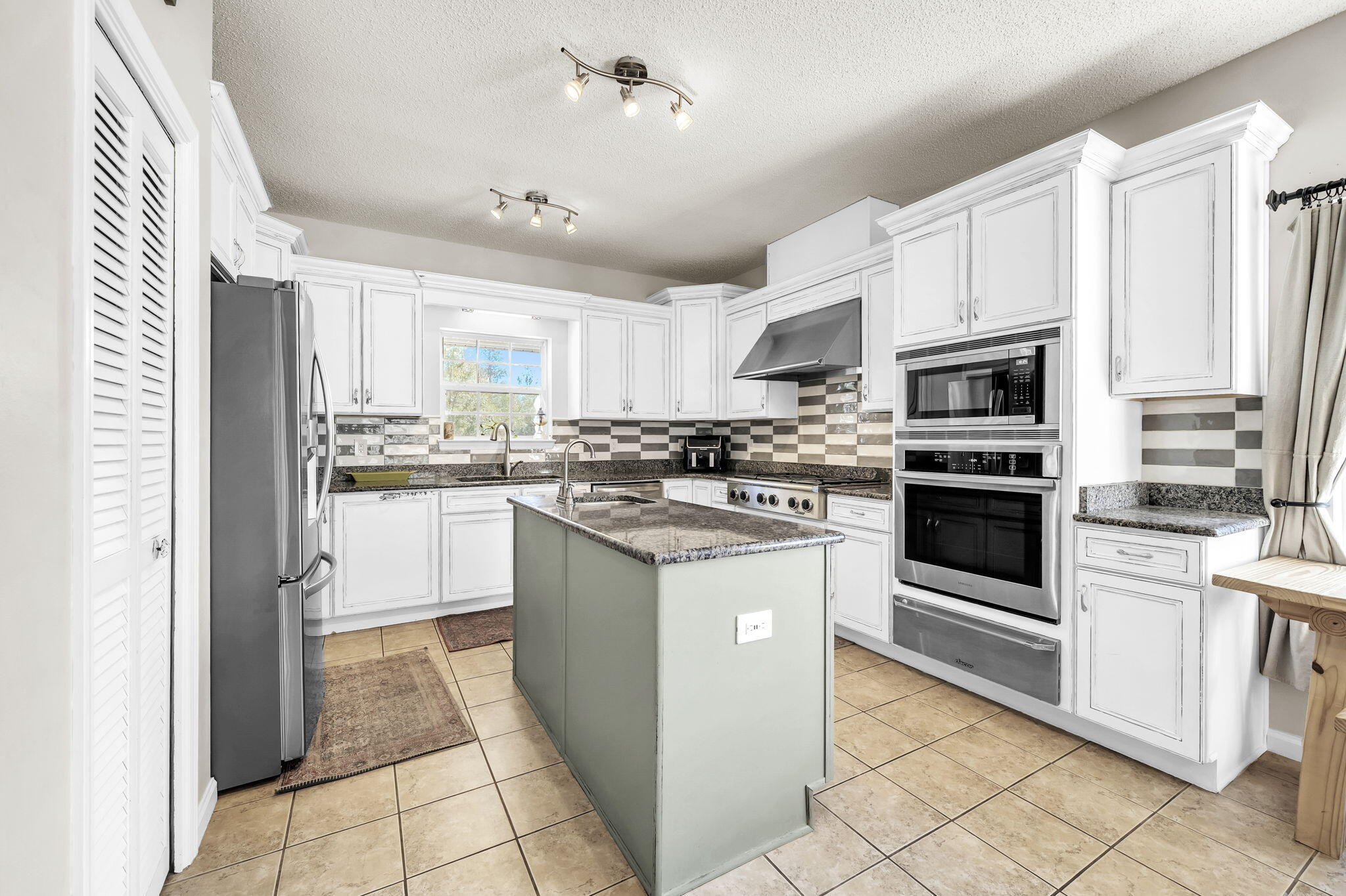 4398 Wilkerson Bluff Road Holt, FL 32564 - Photo 30 of 110 a kitchen with stainless steel appliances granite countertop a stove top oven a sink a refrigerator and white cabinets