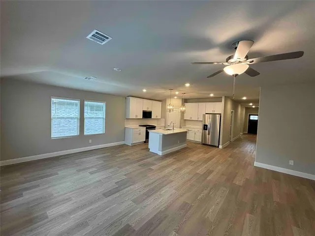 a view of an empty room with a kitchen and wooden floor