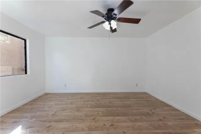 an empty room with wooden floor cabinet and windows