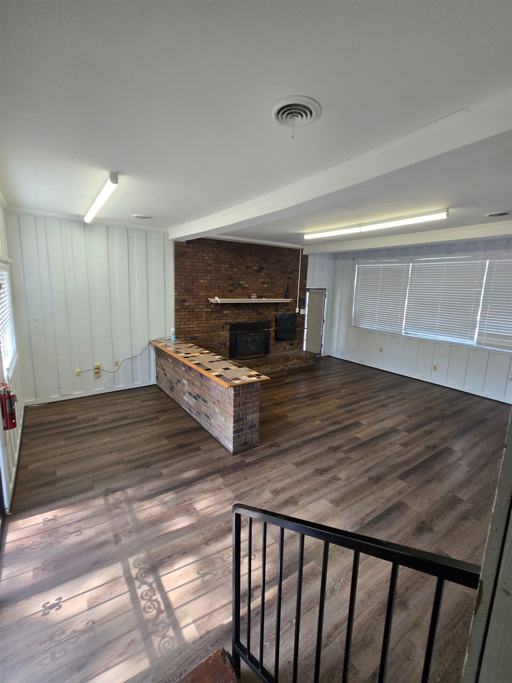 6855 Raleigh Lagrange Road Memphis, TN 38134 - Photo 12 of 13 Unfurnished living room featuring dark wood-type flooring, a brick fireplace, and wood walls
