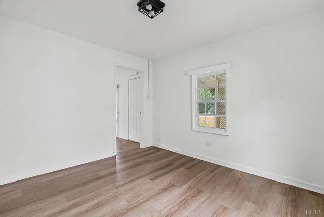 an empty room with wooden floor cabinet and windows