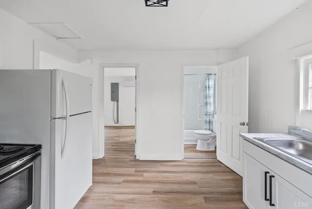 a view of a kitchen with refrigerator and wooden floor