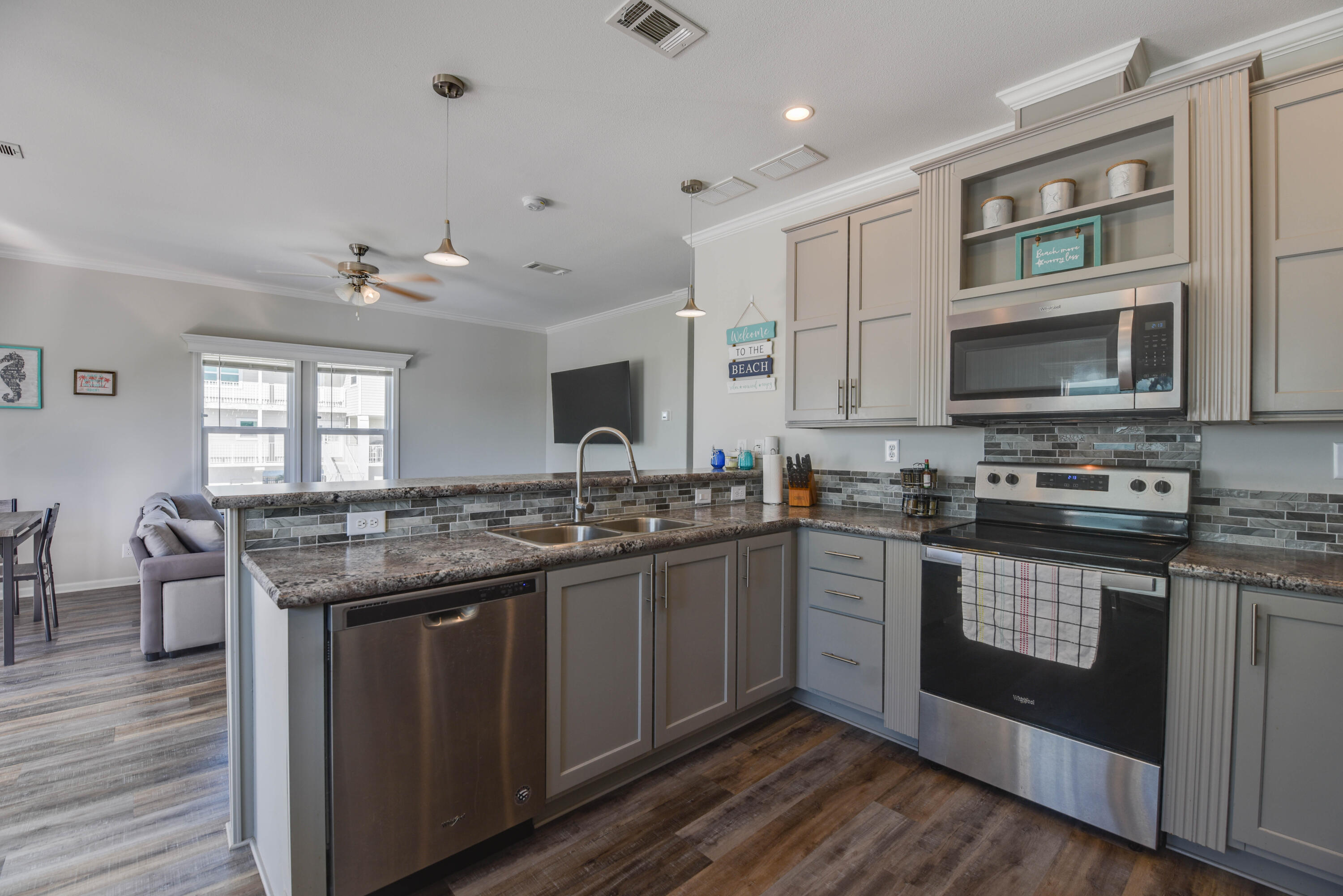 31343 Ave I Big Pine Key, FL 33043 - Photo 6 of 29 a kitchen with stainless steel appliances granite countertop a stove top oven a sink dishwasher a dining table and chairs with wooden floor