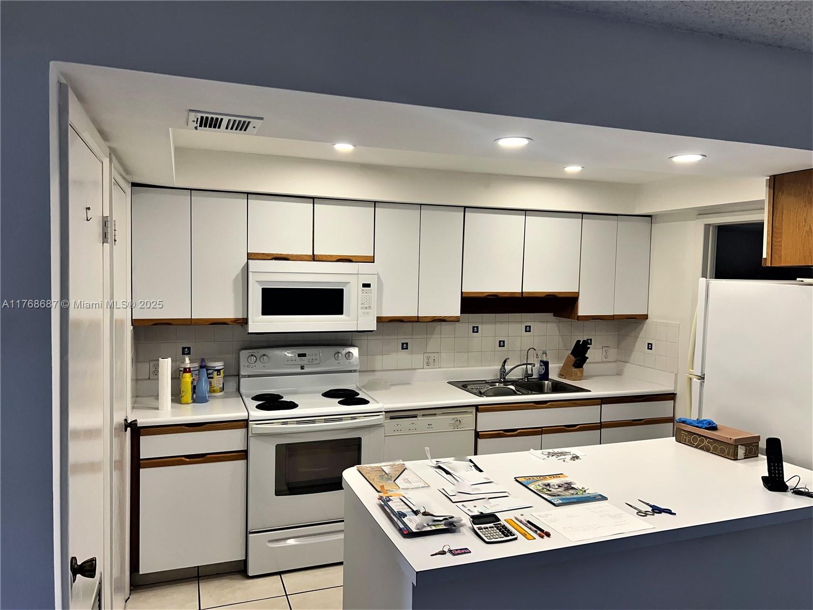 8401 Southwest 107th Avenue, Unit 121E Miami, FL 33173 - Photo 2 of 19 a kitchen with a sink a stove a microwave and cabinets