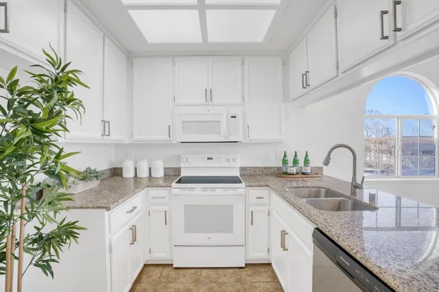 a kitchen with granite countertop a white sink a stove and cabinets