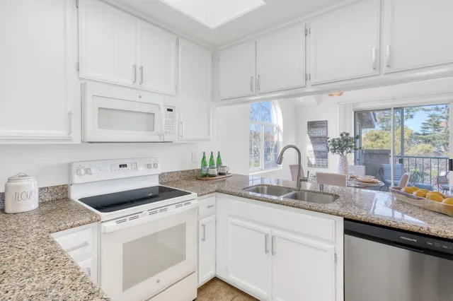 a kitchen with granite countertop white cabinets and white appliances