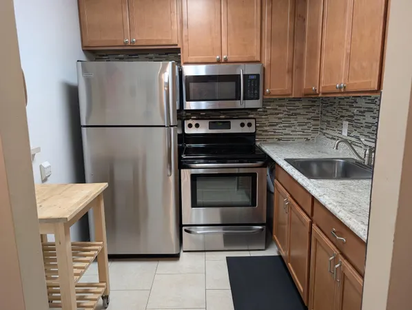 a kitchen with granite countertop a refrigerator stove and microwave
