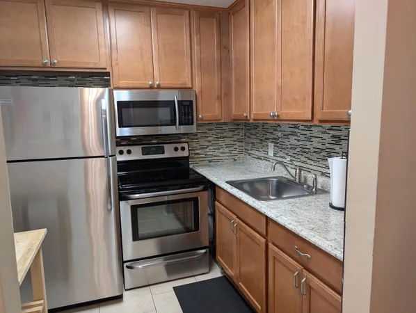 a kitchen with granite countertop a sink stove and refrigerator