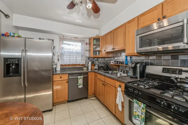 a kitchen with stainless steel appliances kitchen island granite countertop a table chairs in it and wooden floors