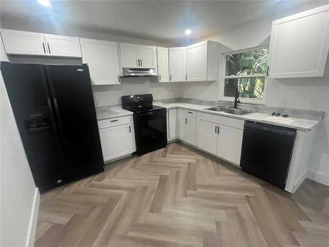 a kitchen with a sink a refrigerator and cabinets
