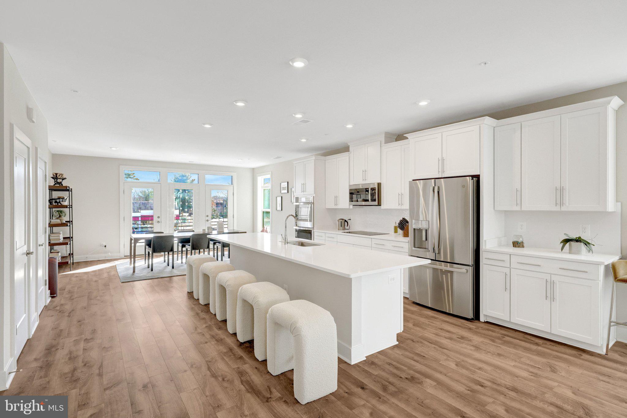 1694 Bandit Loop, Unit 17B Reston, VA 20190 - Photo 2 of 46 a large white kitchen with lots of counter space a refrigerator a table and chairs