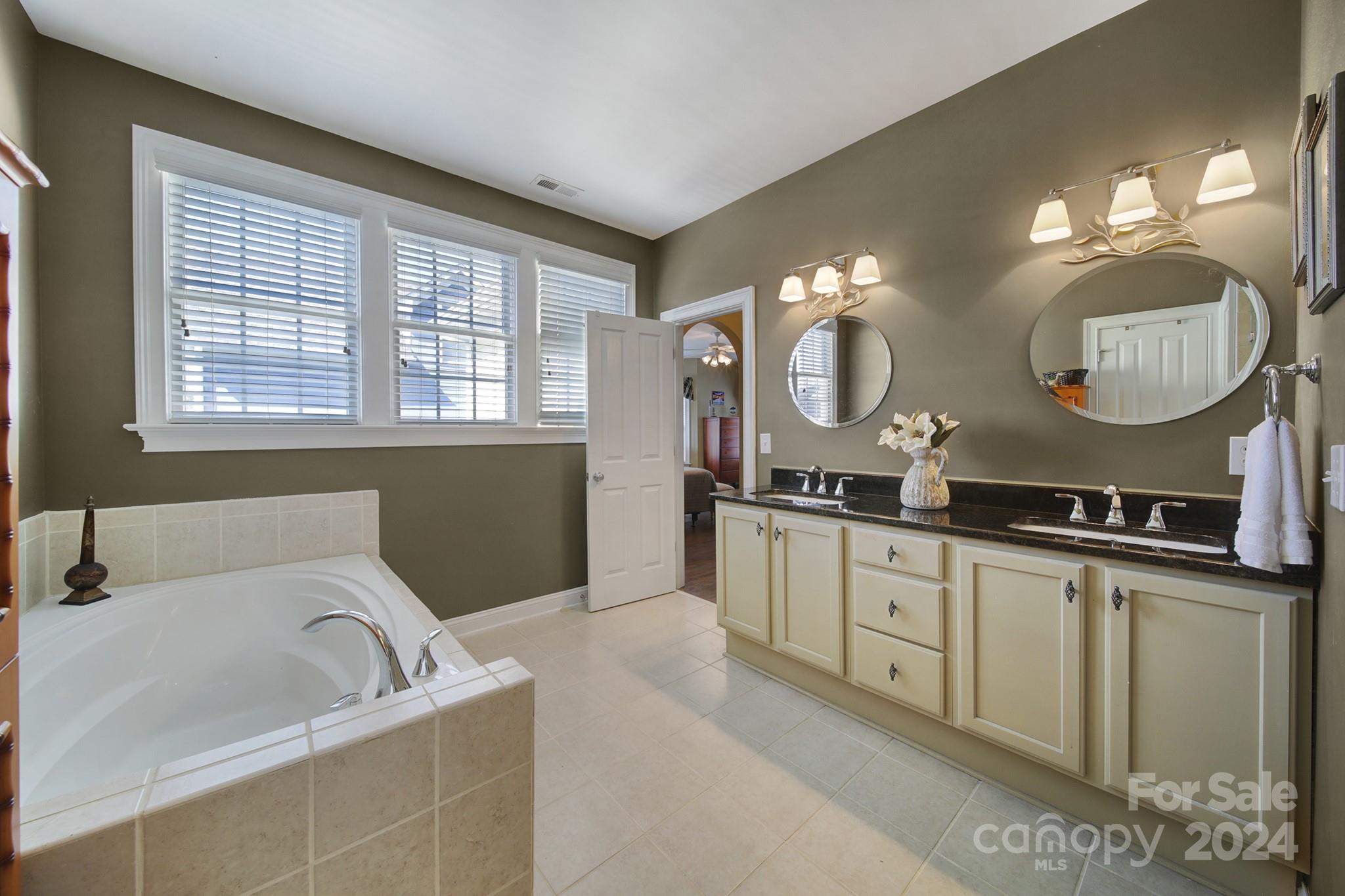 724 Shady Grove Crossing Fort Mill, SC 29708 - Photo 28 of 48 a spacious bathroom with a granite countertop sink a large mirror and a bathtub with shower