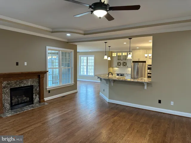 a view of an empty room with wooden floor and a fireplace