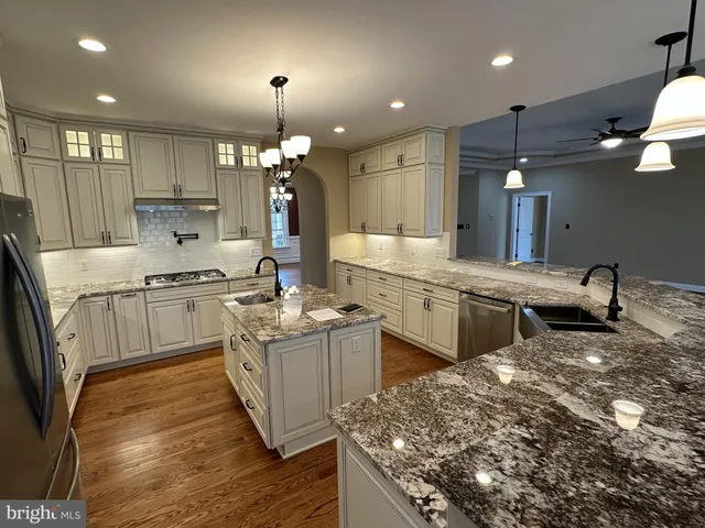a kitchen that has a lot of white cabinets and stainless steel appliances
