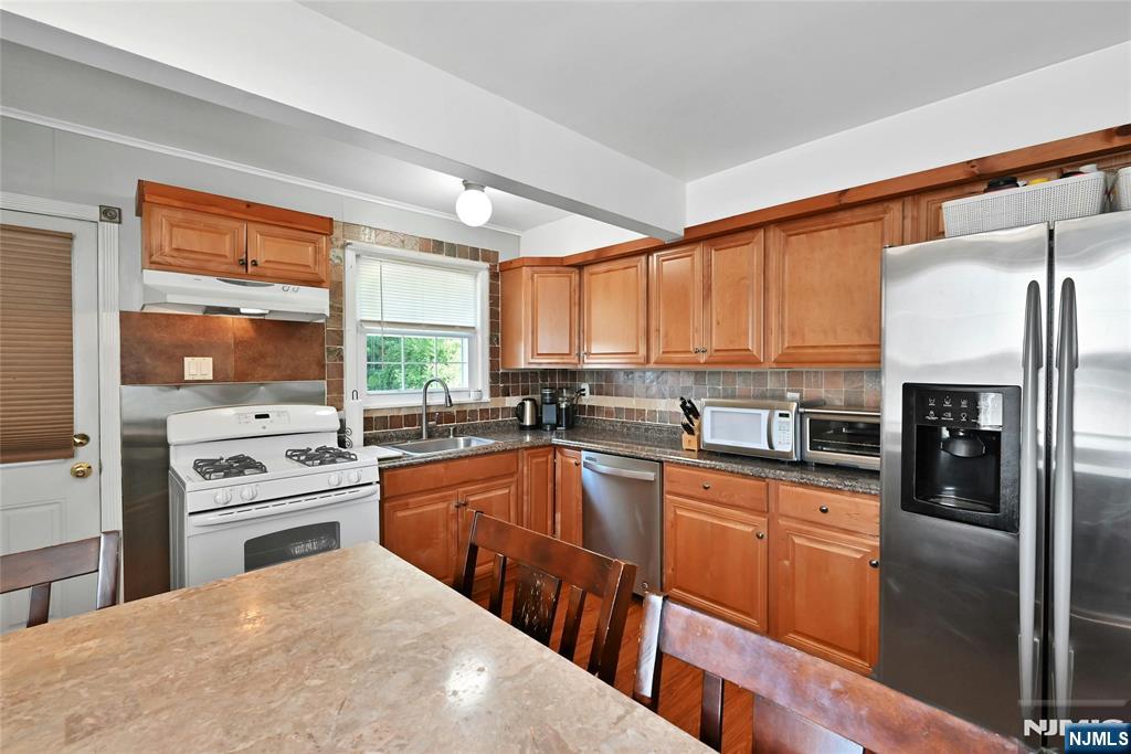 85 Edison Street Clifton, NJ 07013 - Photo 10 of 28 a kitchen with stainless steel appliances granite countertop a refrigerator a sink dishwasher a stove and white countertops with wooden floor