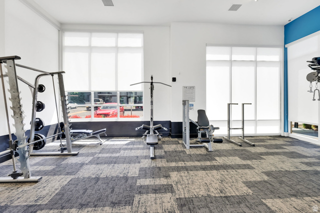 7713 Navarro View Court Midvale, UT 84047 - Photo 37 of 41 Fitness center with large windows, roller shades, high ceilings, and patterned carpet tile flooring
