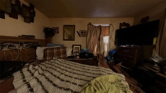 a bedroom with a bed a flat screen tv and dresser