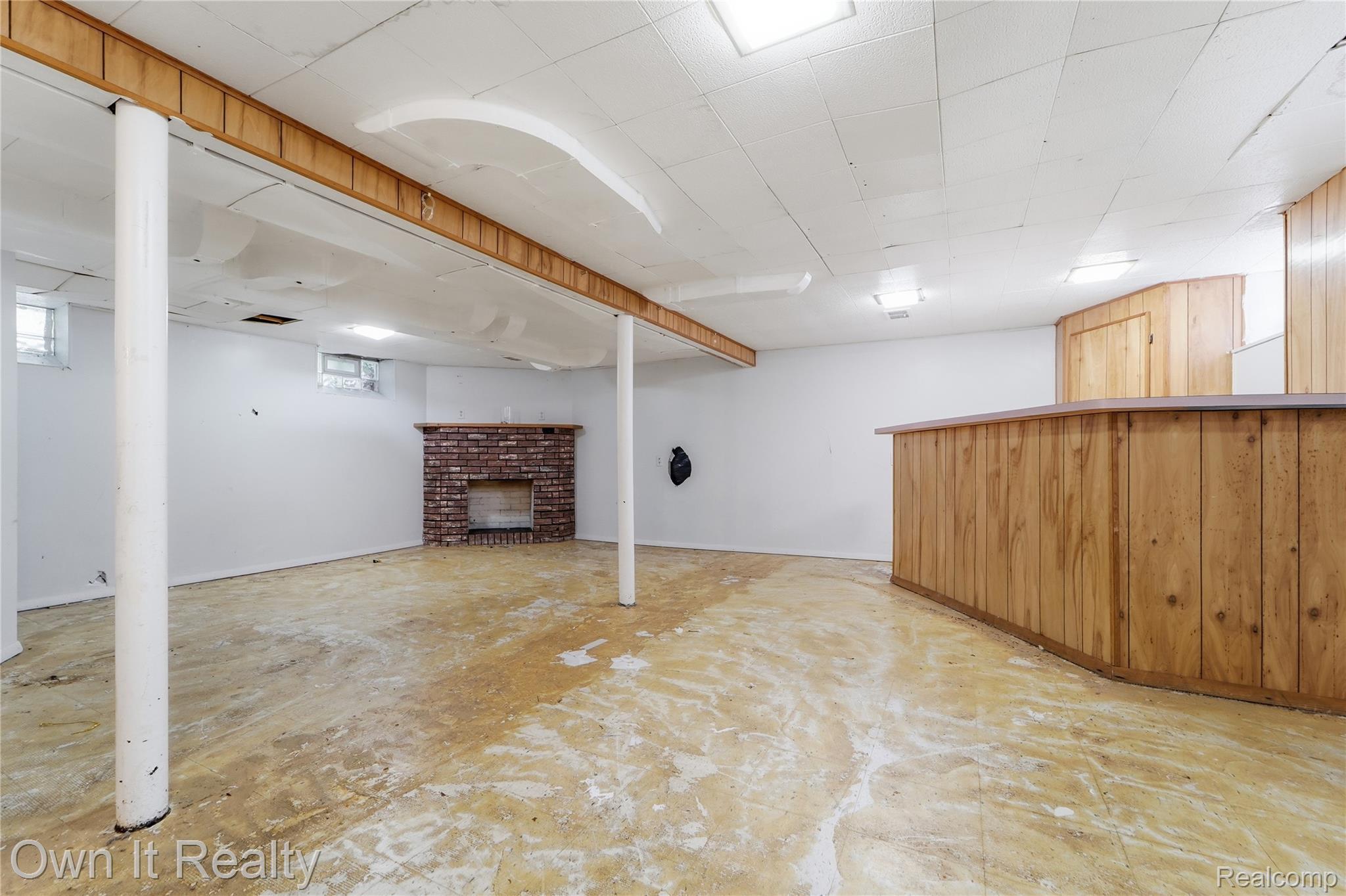 3331 Harding Street Dearborn, MI 48124 - Photo 23 of 31 Spacious lower level featuring a brick fireplace, built-in wood-paneled bar, and drop ceiling with integrated lighting