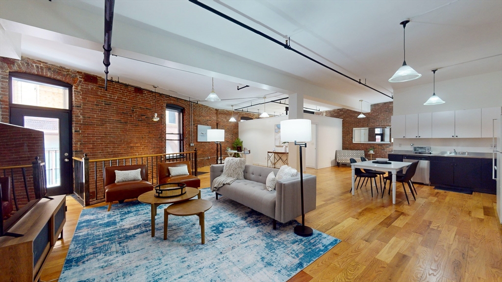 a living room with furniture kitchen view and a wooden floor