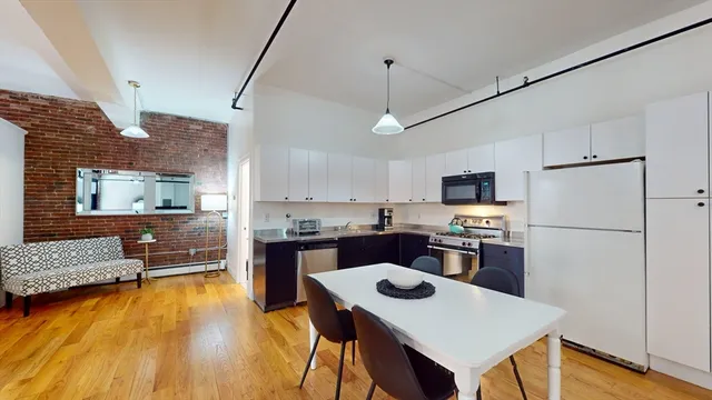 a kitchen with a refrigerator a stove top oven a counter space and wooden floor